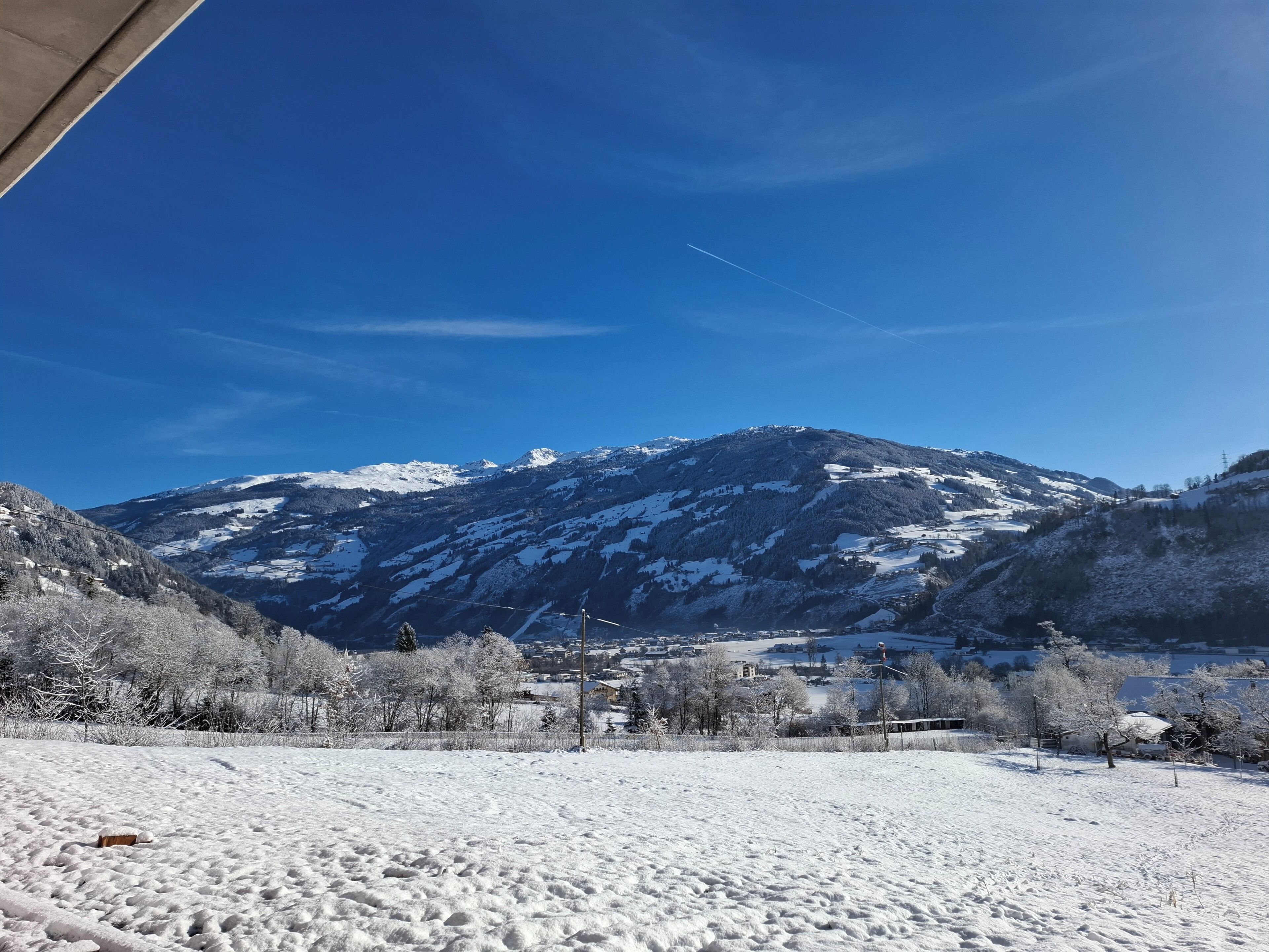 A snow-covered landscape with a mountain in the background and a clear blue sky.
