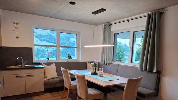 Een moderne keuken met een eetgedeelte, grote ramen en uitzicht op een besneeerd landschap.