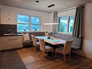 A modern kitchen with a dining area, large windows, and a view of a snowy landscape. - Aussichtsplatz Apartment (Laimach)