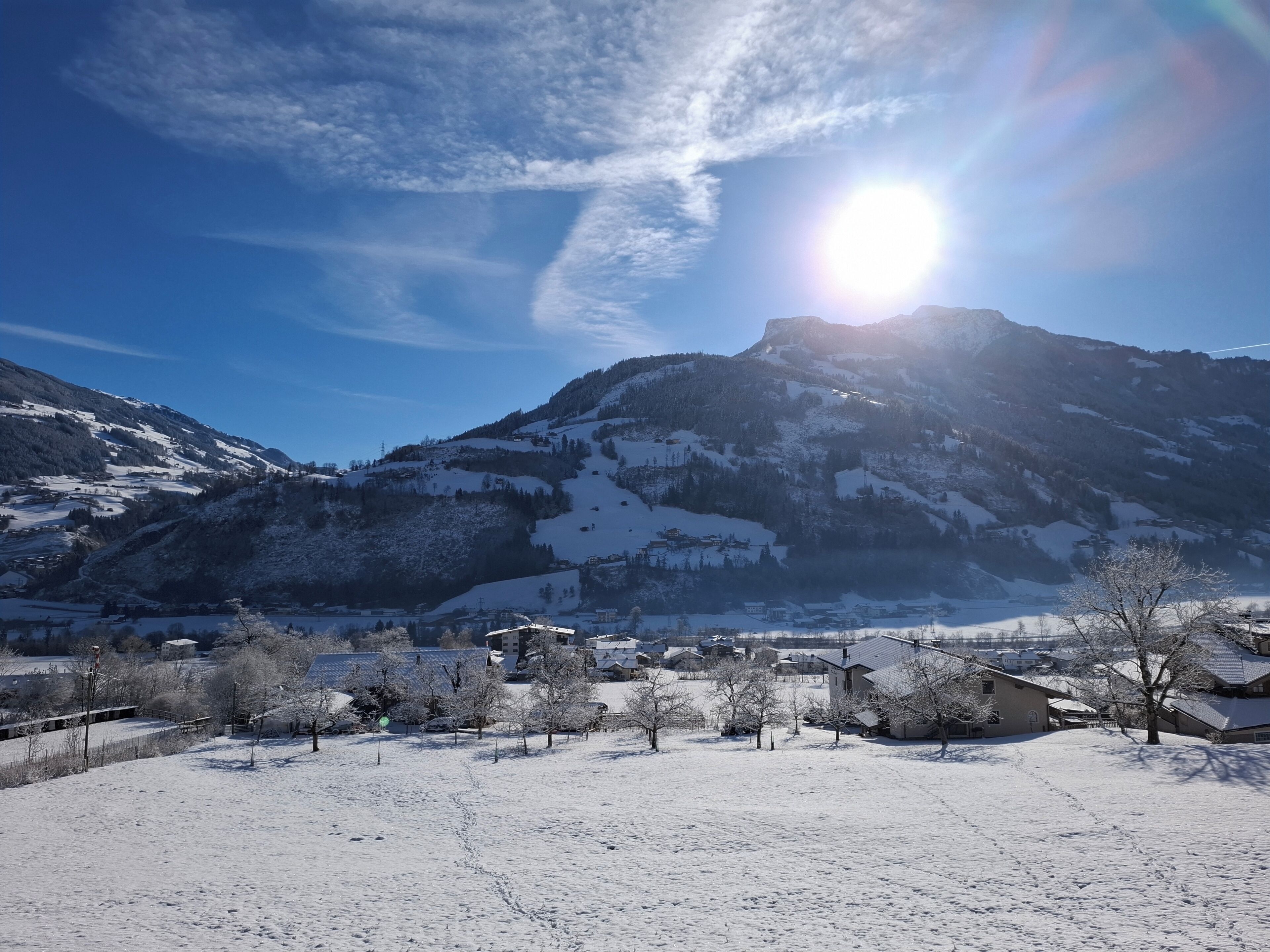 Un paysage enneigé avec une montagne en arrière-plan et un petit village au premier plan.