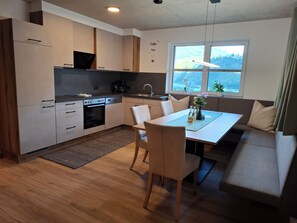 A modern kitchen with a dining area, a sofa, and a window with a view. - Aussichtsplatz Apartment - Mayrhofen-Hippach Vacation Region (Laimach)
