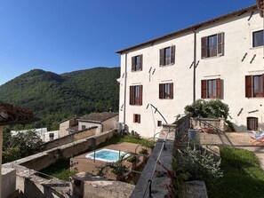 Ein Gebäude mit Pool, umgeben von Grünflächen und Hügeln.