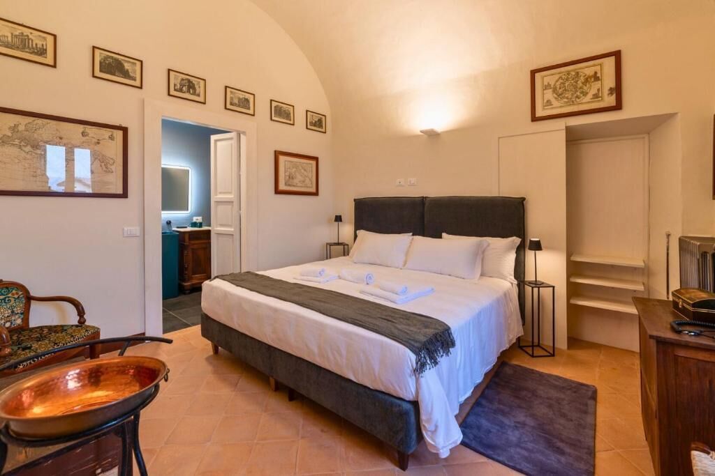 Ein Schlafzimmer mit Bett, Nachttischen, einem Sessel, einem Schreibtisch und gerahmten Bildern an der Wand.