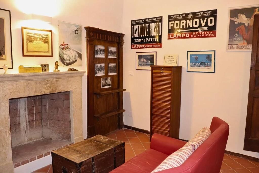 Ein Zimmer mit Kamin, einem roten Sofa und verschiedenen gerahmten Bildern an den Wänden.