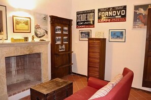 Ein Zimmer mit Kamin, einem roten Sofa und verschiedenen gerahmten Bildern an den Wänden.