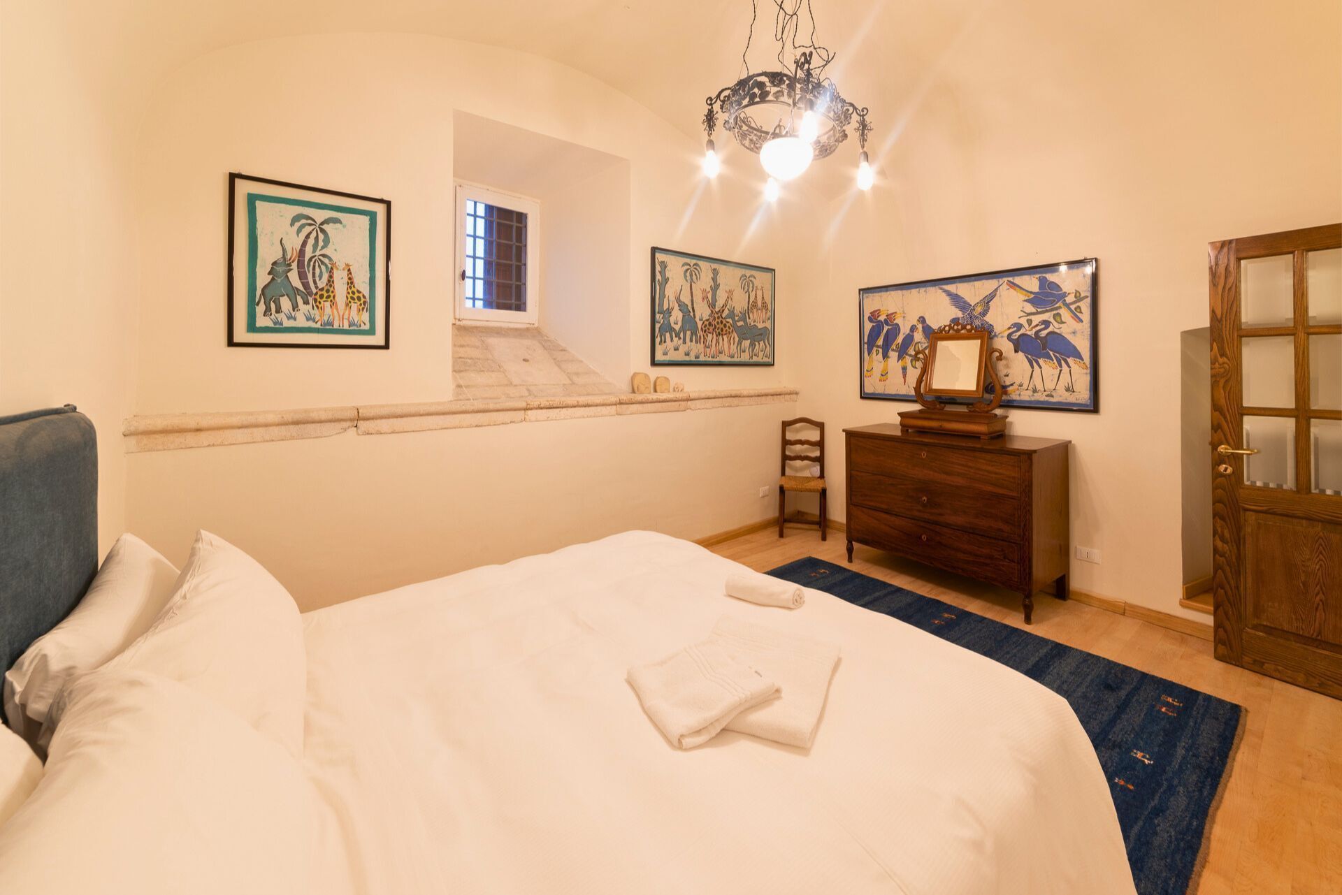 A bedroom with a bed, a dresser, a chair, and artwork on the walls.