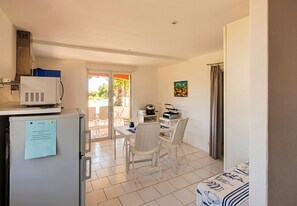 A compact kitchen with a refrigerator, microwave, and a small dining area with chairs and a table. - CASA-Jeanne, piscine et vue mer pour 4 (Cavalaire-sur-Mer)