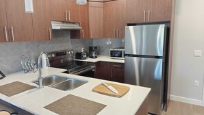 Una cocina moderna con electrodomésticos de acero inoxidable, armarios de madera y una isla central con tabla de cortar.