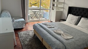 Una camera d'albergo con un letto, una sedia, una scrivania e un balcone con tavolo e sedie.
