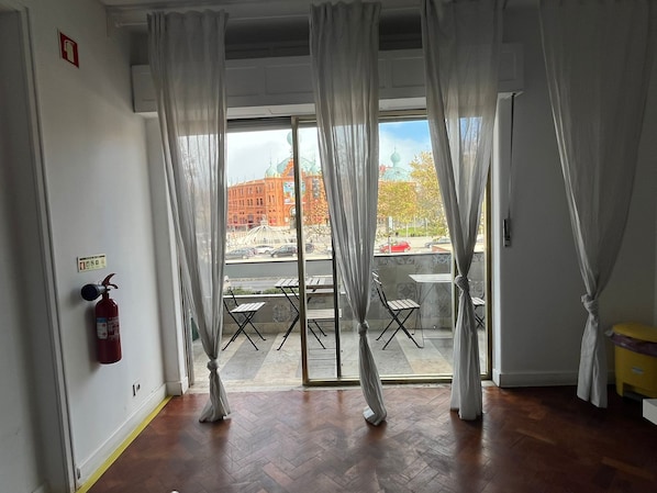 Une piĂšce Ă©quipĂ©e dâun extincteur, avec vue sur un bĂątiment surmontĂ© dâun dĂŽme, et une table Ă lâextĂ©rieur.