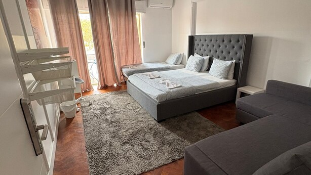 Una camera da letto con un letto, una poltrona, un appendiabiti e una finestra con tende.