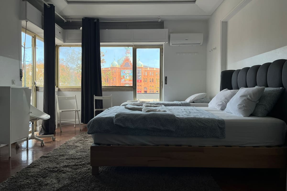Un dormitorio moderno con una cama grande, un escritorio y vistas a un edificio rojo.