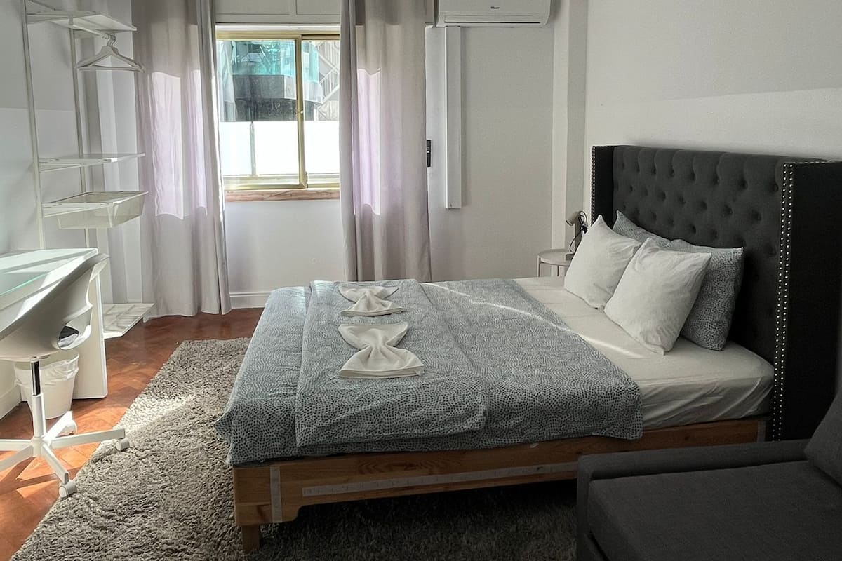 Un dormitorio con cama, mesita de noche y escritorio.