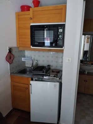 Una cocina compacta con microondas, estufa y lavaplatos.