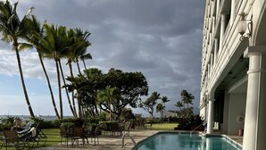 Un área de piscina con un jacuzzi, sillas de descanso y palmeras.