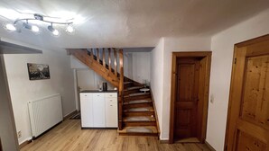 A wooden staircase leading to a landing, a white radiator, a small cabinet, and a wooden door.