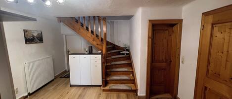 A wooden staircase leading to a landing, a white radiator, a small cabinet, and a wooden door.