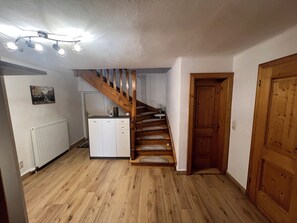 A wooden staircase leading to a landing, a white radiator, a small cabinet, and a wooden door. - Vacation Home with a Garden in the Salzburg Lake District – Experience Lakes, Nature, and the City (Köstendorf bei Salzburg)