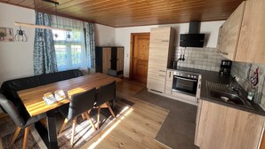 A modern kitchen with wooden cabinets, a built-in oven, and a dining area with a wooden table and chairs.