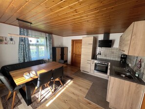 A modern kitchen with wooden cabinets, a built-in oven, and a dining area with a wooden table and chairs. - Vacation Home with a Garden in the Salzburg Lake District – Experience Lakes, Nature, and the City (Köstendorf bei Salzburg)