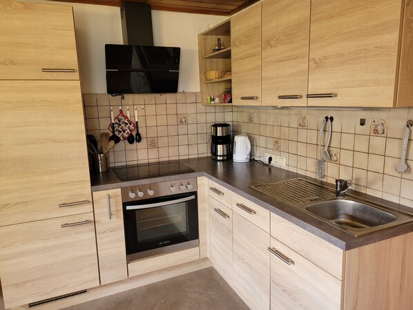 Una cocina con armarios de madera, estufa, pileta y microondas.