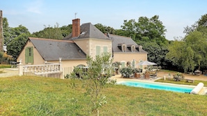 Une maison à deux étages avec une piscine, un jardin et un petit espace patio.