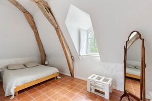 A bedroom with a bed, a mirror, and a window.