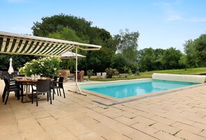 Ein Poolbereich mit Tisch und Stühlen, einer Pergola und einem Schwimmbecken.