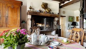 Un coin repas avec une table préparée pour le thé, une cheminée et un buffet en bois.