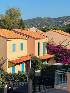 Eine Reihe von Gebäuden im mediterranen Stil mit Terrakotta-Dächern, einem schwarzen Tor und einem geparkten Auto davor.