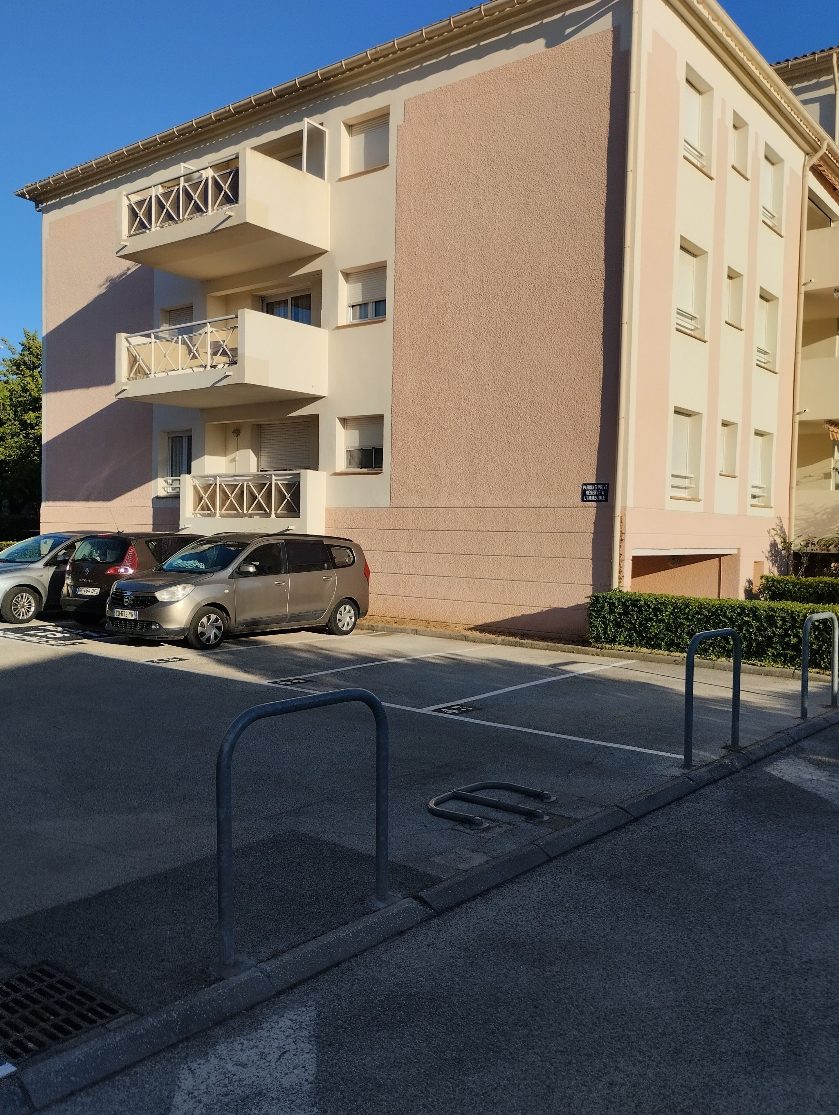 Ein mehrstöckiges Gebäude mit Balkonen, einem Parkplatz und einem Schild, das freie Parkplätze anzeigt.