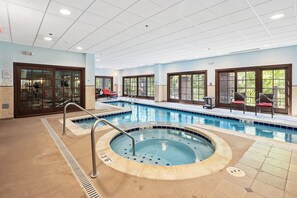 Ein Swimmingpool mit Whirlpool, Liegestühlen und Blick ins Freie.