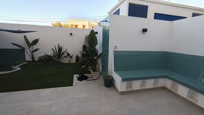 A small outdoor patio with a green bench, a small pool, and various plants. - 2-Bedroom Apartment with a Jacuzzi (Marsa)