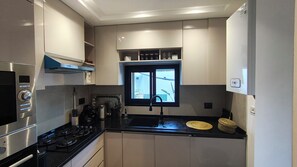Eine kleine Küche mit Herd, Backofen und einem Fenster über der Spüle.