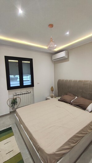 Ein Schlafzimmer mit Bett, Fenster, Klimaanlage und Heizkörper.