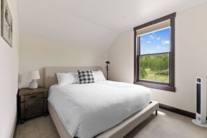 A bedroom with a bed, nightstand, lamp, window, and radiator. - Pet-Friendly with Mountain Views - Minutes from Maryland Creek Dog Park (Silverthorne)