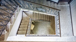 A staircase with a metal railing, carpeted steps, and a handrail.