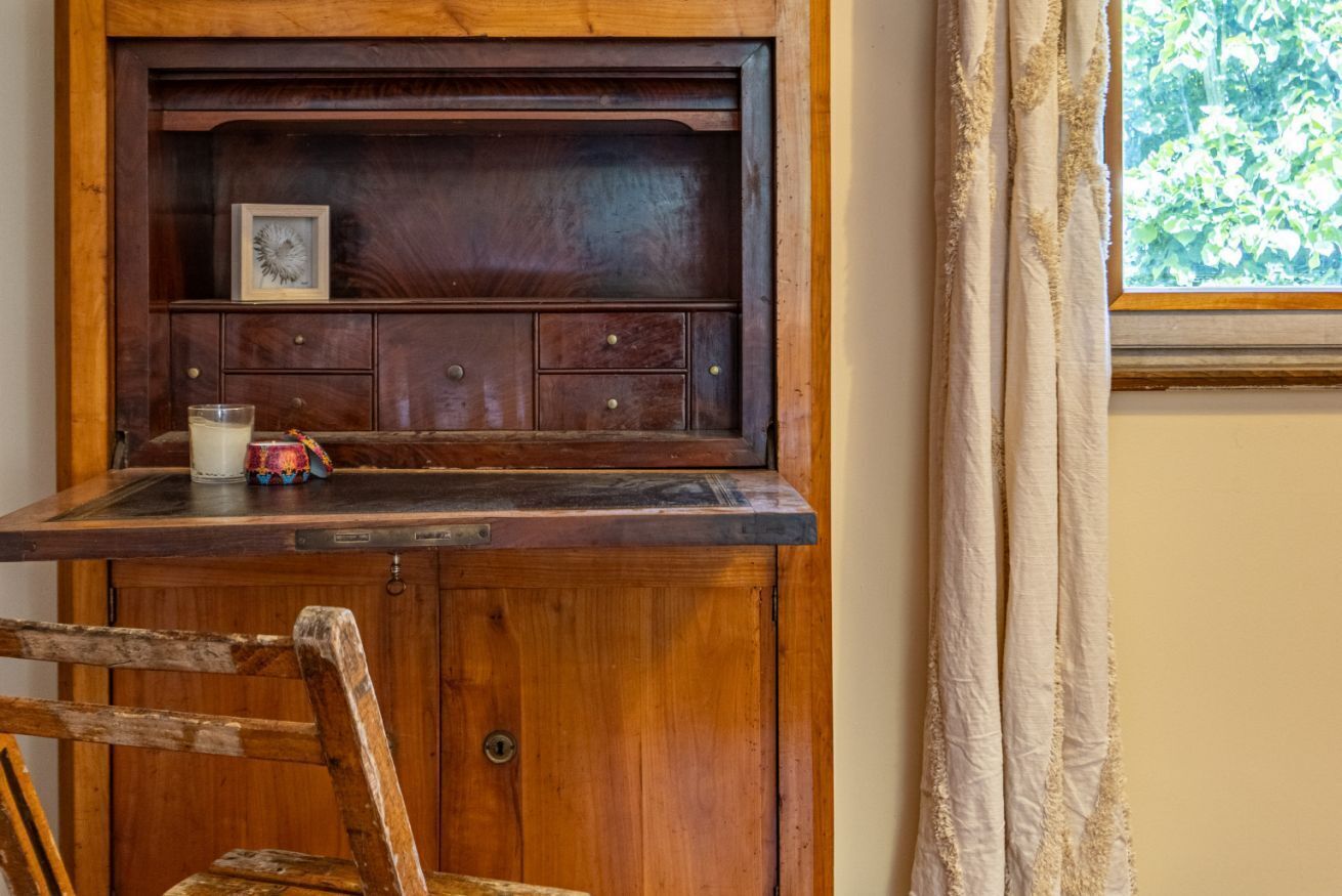 Un aparador de madera con un estante, un cuadro enmarco y una vela sobre una mesa.
