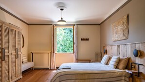 A bedroom with a bed, a window, a radiator, and a wooden headboard.
