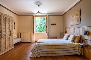 Una camera da letto con un letto, una finestra, un termosifone e una testiera in legno.