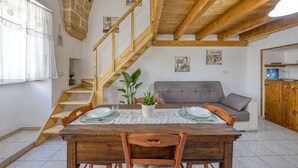 Ein Essbereich mit Holztisch, Stühlen, einer Treppe, einer Couch und einem Holzschrank.