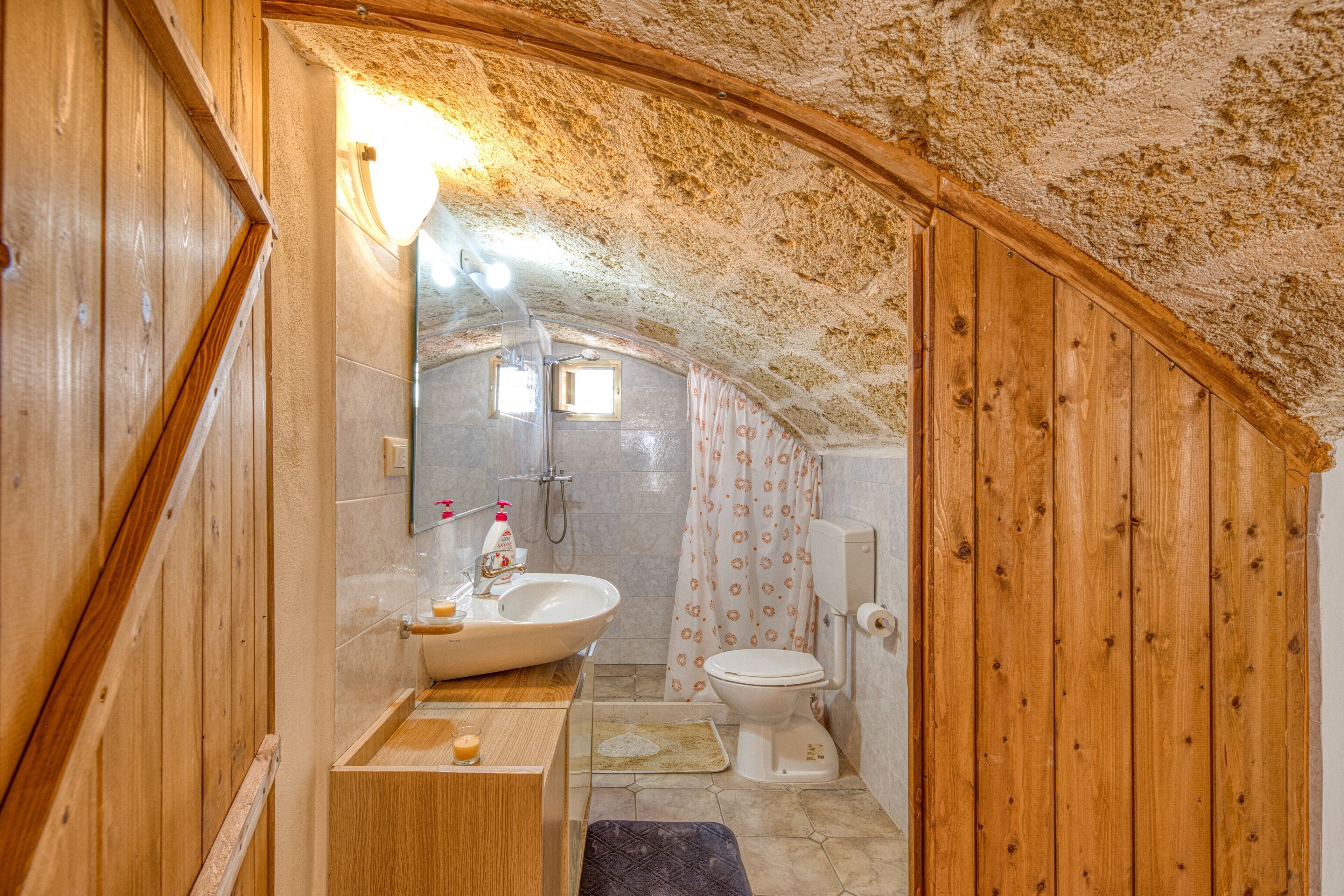 Ein kleines Badezimmer mit Holzvertäfelung, einem Waschbecken, einer Toilette und einer Duschkabine.