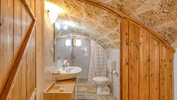 Ein kleines Badezimmer mit Holzvertäfelung, einem Waschbecken, einer Toilette und einer Duschkabine.