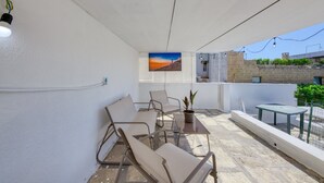 Ein Balkon mit Tisch, Stühlen, einem Blumentopf und einem Gemälde.