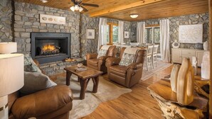 Una sala de estar acogedora con chimenea de piedra, muebles de cuero y un comedor con vistas.