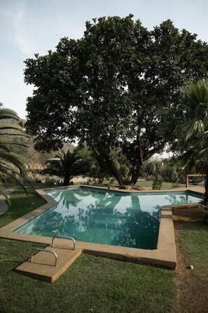 Una piscina rodeada de césped y árboles.