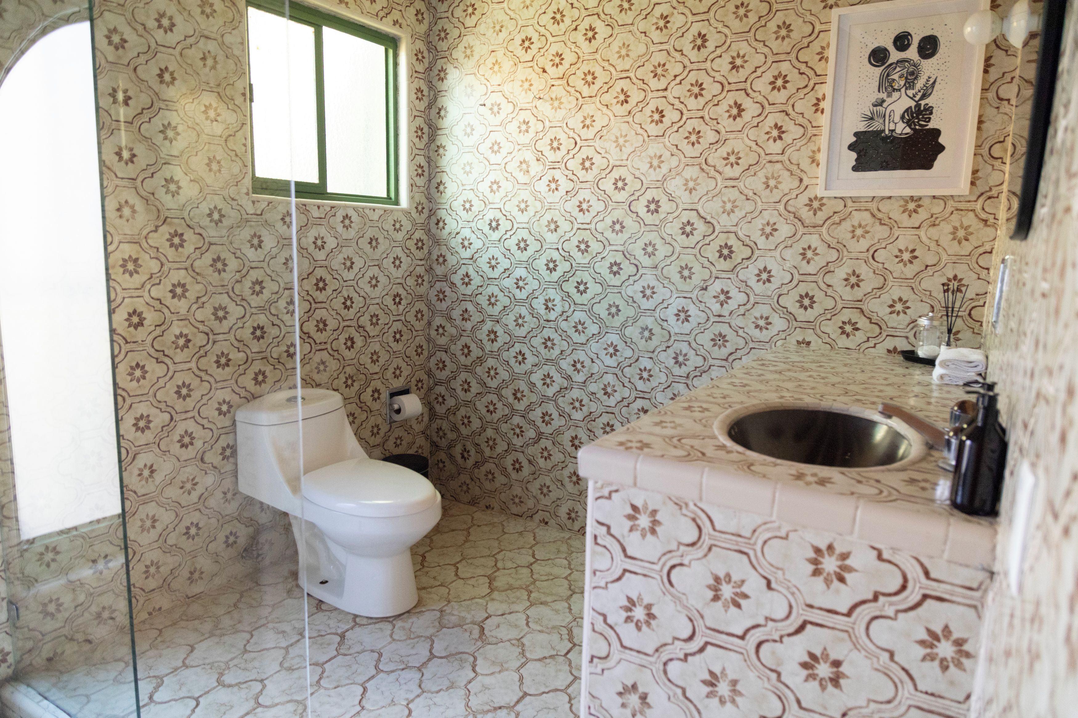 Une salle de bain avec des toilettes, un lavabo et des murs à motifs.