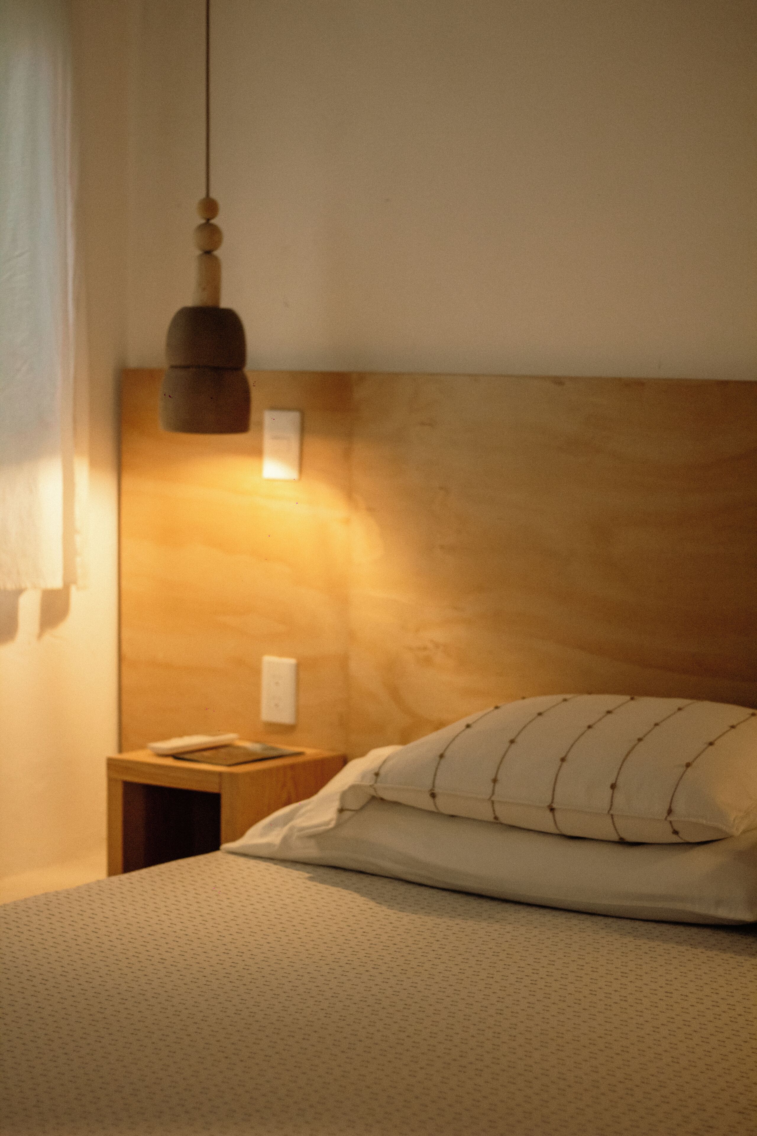 Un lit avec un oreiller blanc et une tête de lit en bois.