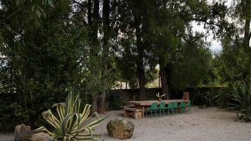 Un patio con mesa y sillas, rodeado de árboles y plantas.
