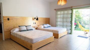 Un dormitorio con dos camas de madera, una lámpara de pared y vistas al exterior.